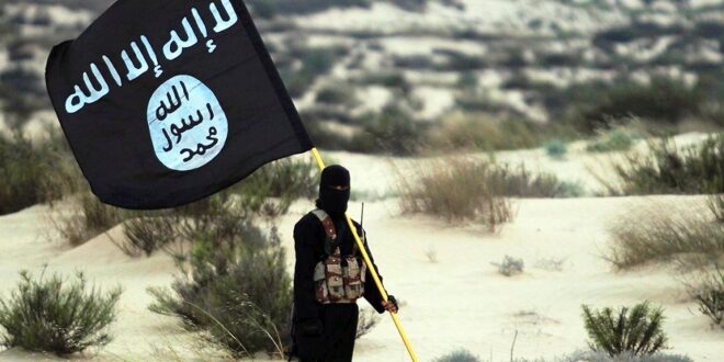 masked islamic state soldier poses holding the isil banner in the desert 2015