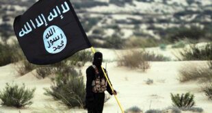 masked islamic state soldier poses holding the isil banner in the desert 2015